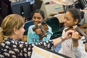 Two new orchestra members pick up violins for the first time in their lives. (Photo by Timmy H.M. Shen)